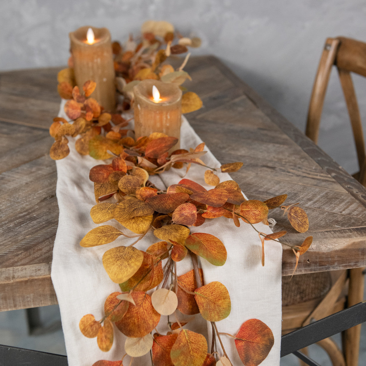 Farmhouse table with thanksgiving garland and fake flame candles in the color of wheat