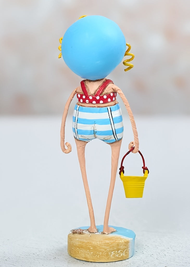 Lori Mitchell Sandy at the Beach figurine wearing a red, white, and blue bathing suit.