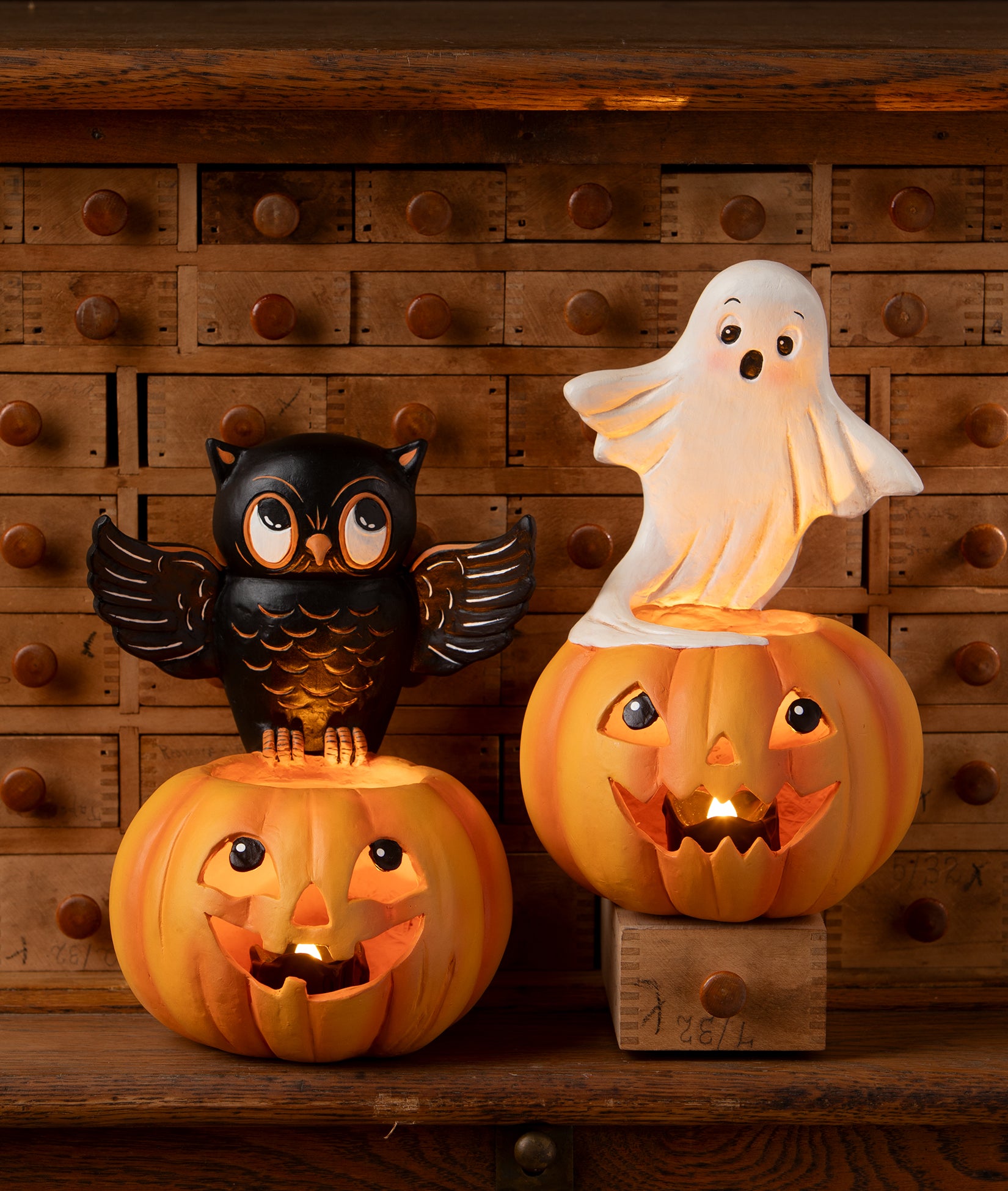 Cute Halloween decor with an owl, a ghost, and jack-o-lantern candle holders decorating an antique spice cabinet. Part of the Bethany Lowe Halloween Collection.