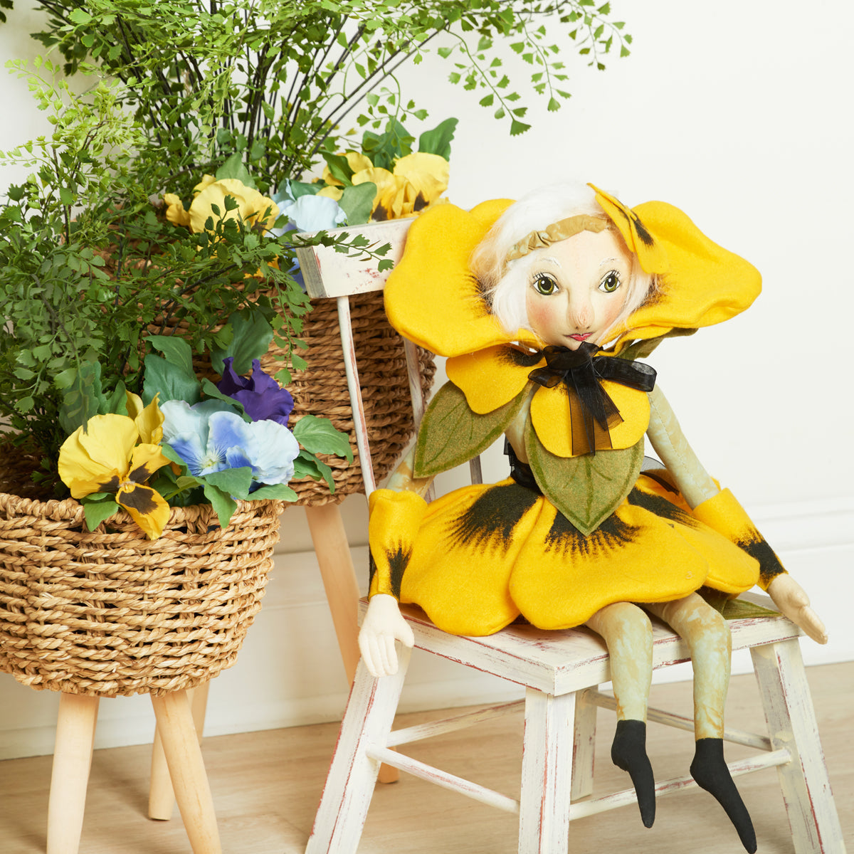 Paulina Pansy flower doll sitting in a chair with Easter decor