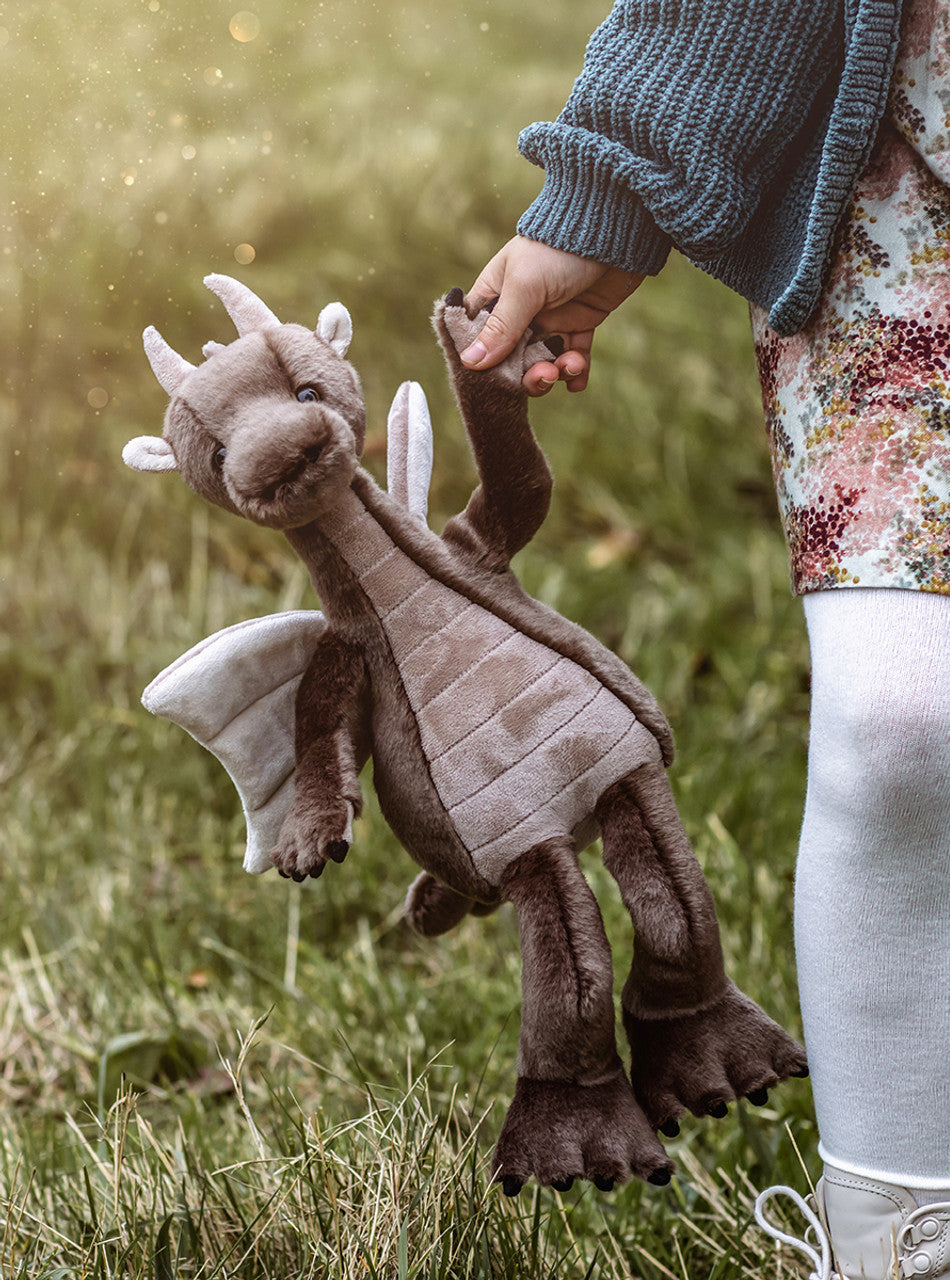 Child carrying brown plush dragon Clubs by Charlie Bears