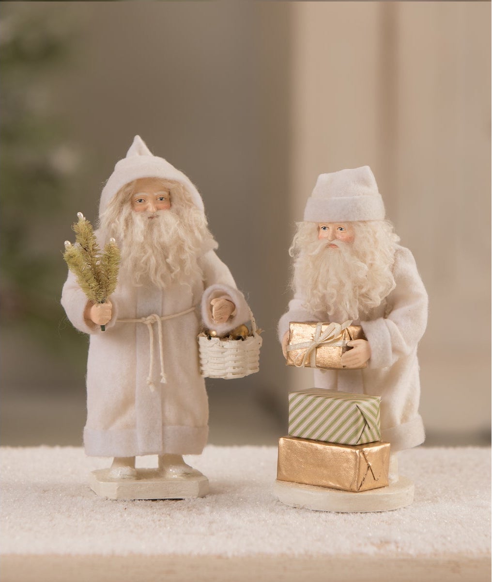 santa dressed in white Inspiring Conversations with Carl of Carl Atlanta, LLC dba Jolly Santa Blue Eyes Voyage ATL Magazine holding with a gift bag and a present Dreaming of White Christmas Santa